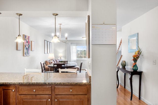 kitchen featuring decorative light fixtures, light stone countertops, and light hardwood / wood-style flooring