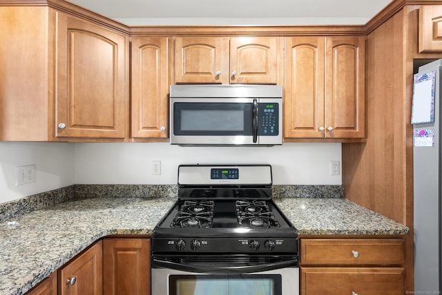 kitchen with light stone counters and appliances with stainless steel finishes