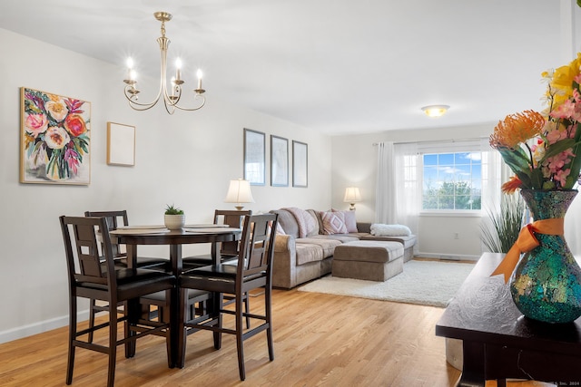 dining room featuring light wood-type flooring and a chandelier