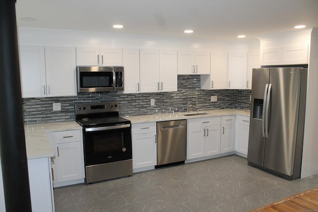 kitchen featuring backsplash, light stone counters, stainless steel appliances, sink, and white cabinetry