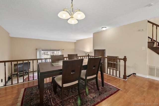 dining space with hardwood / wood-style floors and a chandelier