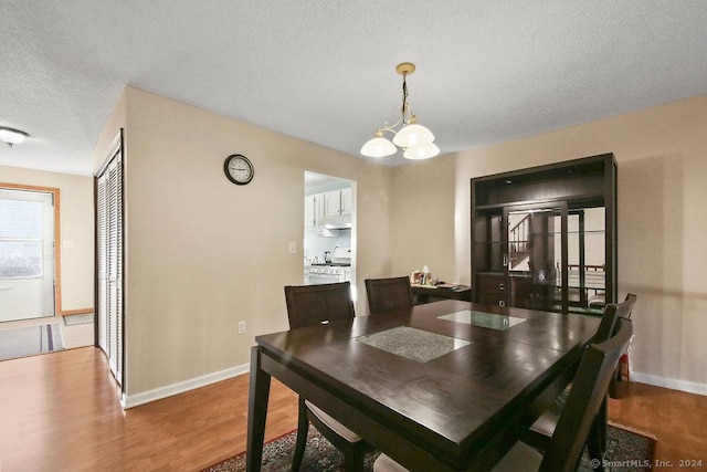 dining room with wood-type flooring, a textured ceiling, and a notable chandelier