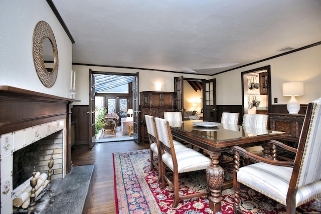 dining area featuring dark hardwood / wood-style floors, ornamental molding, a fireplace, and french doors