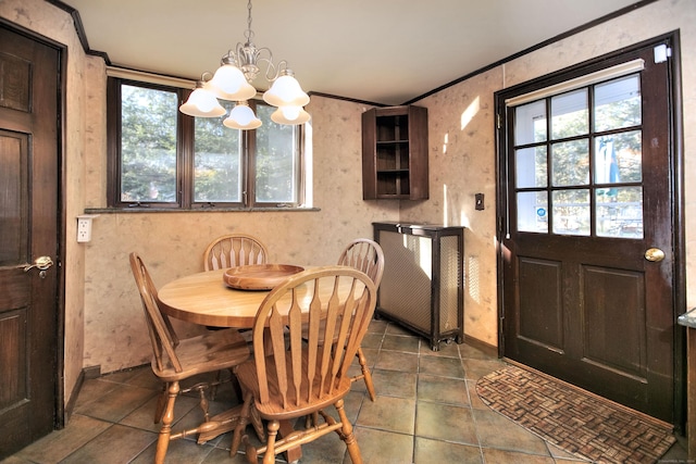 dining space with dark tile patterned floors, a healthy amount of sunlight, ornamental molding, and a chandelier