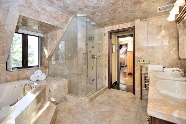 bathroom with vanity, independent shower and bath, and tile walls