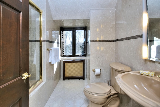 full bathroom with tile patterned flooring, sink, radiator heating unit, and tile walls