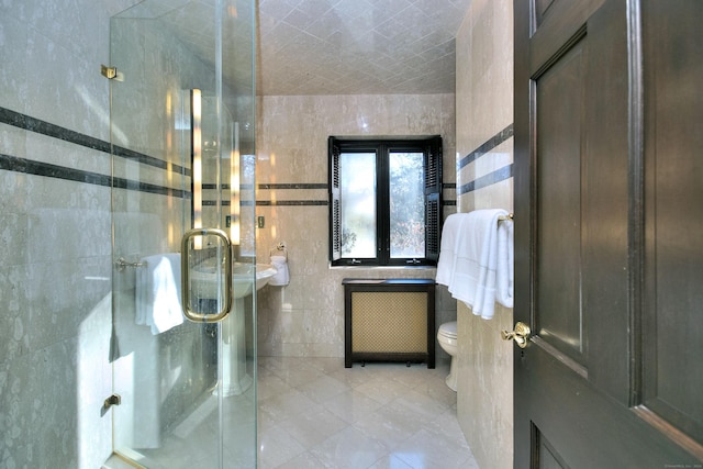 bathroom with radiator heating unit, a shower with door, tile walls, and toilet