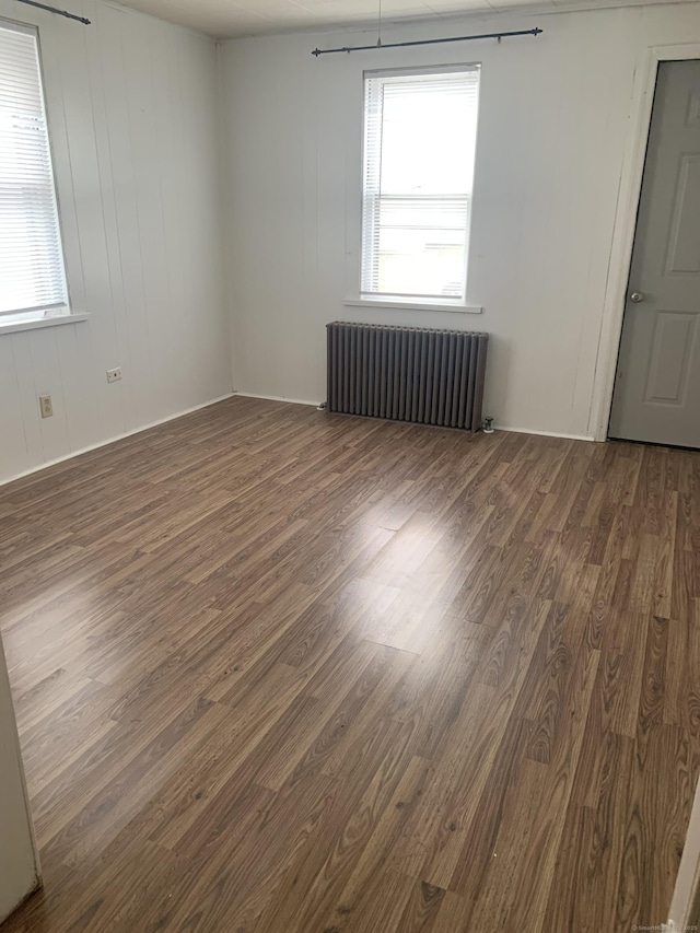 empty room featuring dark wood-type flooring and radiator