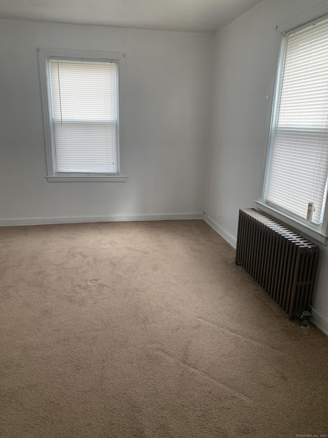 carpeted empty room featuring radiator and a wealth of natural light