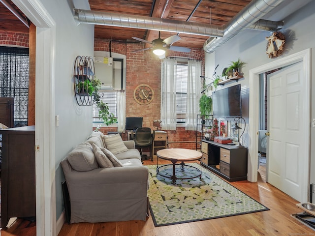 living room featuring beam ceiling, ceiling fan, brick wall, light hardwood / wood-style floors, and wood ceiling