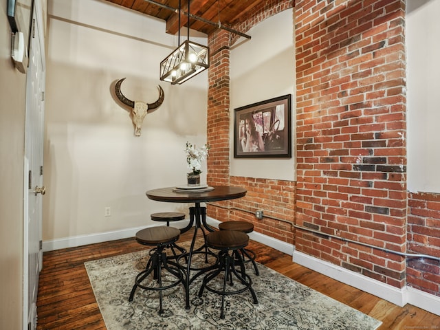 dining space with wood ceiling, dark hardwood / wood-style flooring, and brick wall