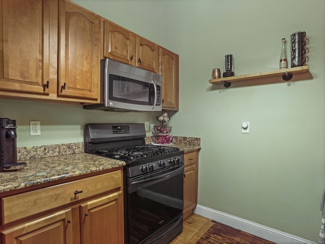 kitchen featuring light stone countertops, light wood-type flooring, and black range with gas cooktop