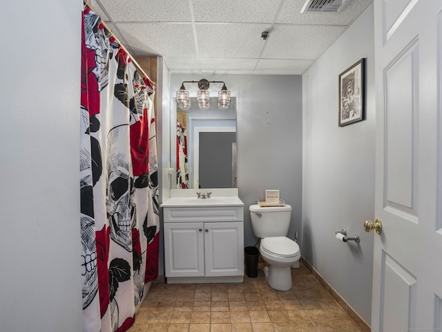 bathroom featuring vanity, toilet, and a drop ceiling