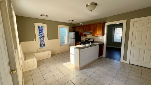 kitchen with decorative backsplash, sink, light tile patterned floors, and stainless steel appliances