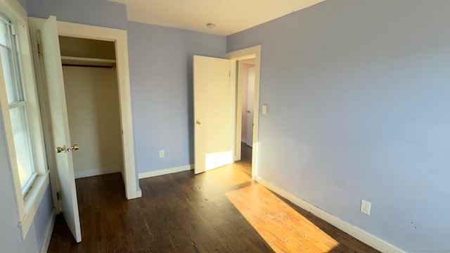 unfurnished bedroom featuring dark hardwood / wood-style flooring and a closet