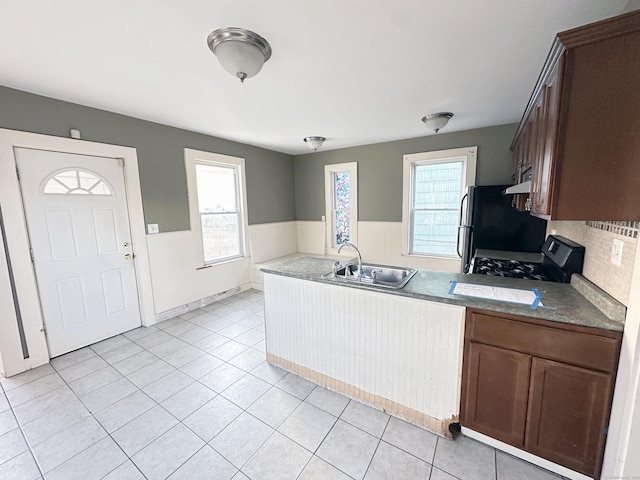 kitchen with backsplash, sink, black appliances, range hood, and light tile patterned flooring