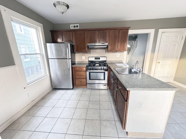 kitchen with sink, stainless steel appliances, tasteful backsplash, dark brown cabinets, and light tile patterned floors