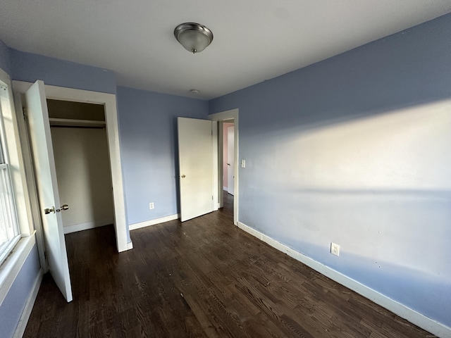 unfurnished bedroom with dark hardwood / wood-style floors and a closet