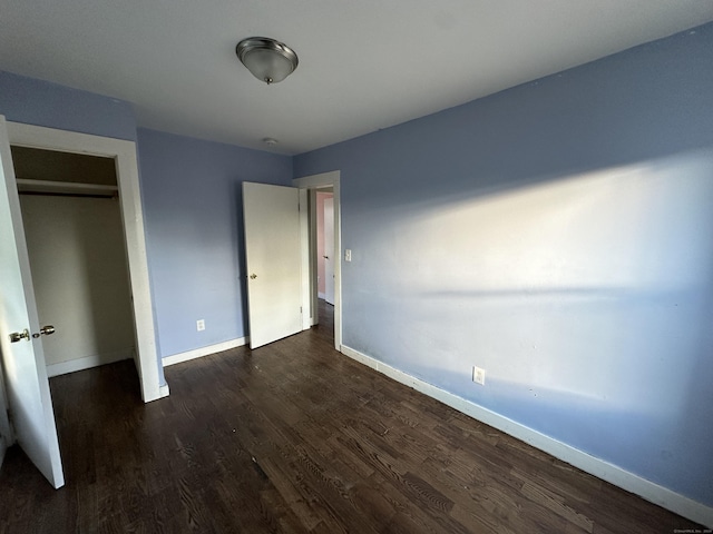 unfurnished bedroom featuring a closet and dark wood-type flooring