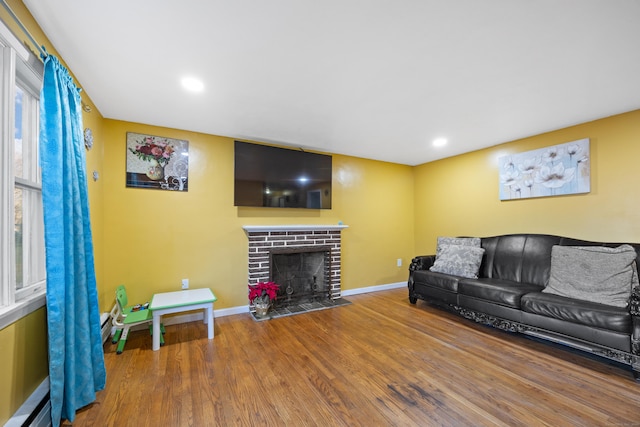 living room with hardwood / wood-style flooring, a fireplace, and a baseboard heating unit