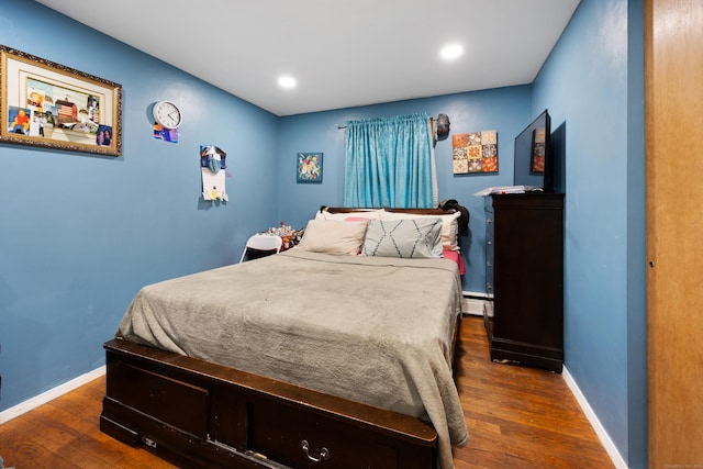 bedroom with baseboard heating and dark hardwood / wood-style floors