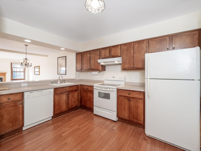 kitchen featuring light wood-type flooring, white appliances, sink, a chandelier, and hanging light fixtures