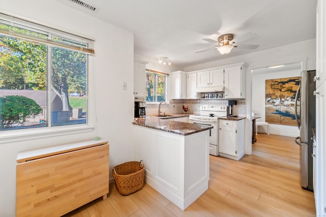 kitchen featuring white cabinetry, white electric range oven, stainless steel fridge, dark stone counters, and light wood-type flooring