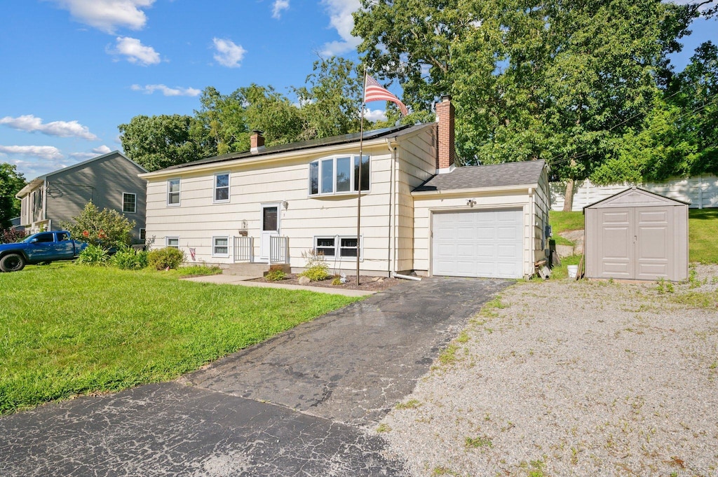 split foyer home with a front yard, a shed, and a garage