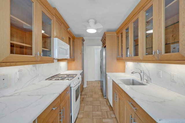 kitchen with decorative backsplash, light stone countertops, white appliances, and sink