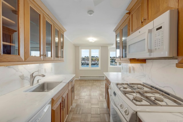 kitchen featuring backsplash, light stone counters, white appliances, baseboard heating, and sink