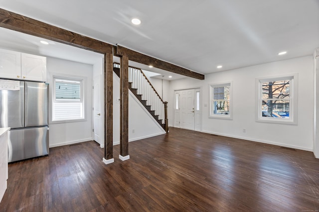 unfurnished living room with beamed ceiling and dark wood-type flooring