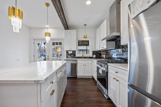 kitchen featuring white cabinetry, wall chimney exhaust hood, stainless steel appliances, and decorative light fixtures