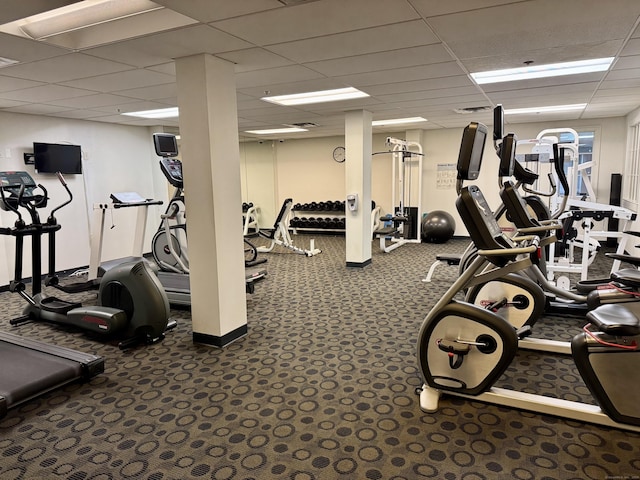 gym featuring dark carpet and a drop ceiling