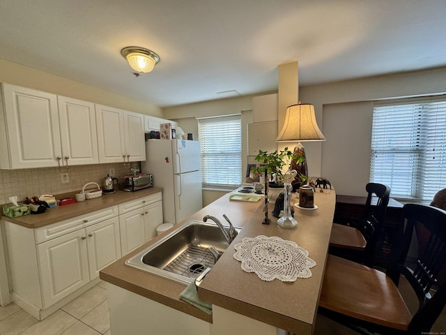 kitchen with white cabinets, white refrigerator, sink, and tasteful backsplash