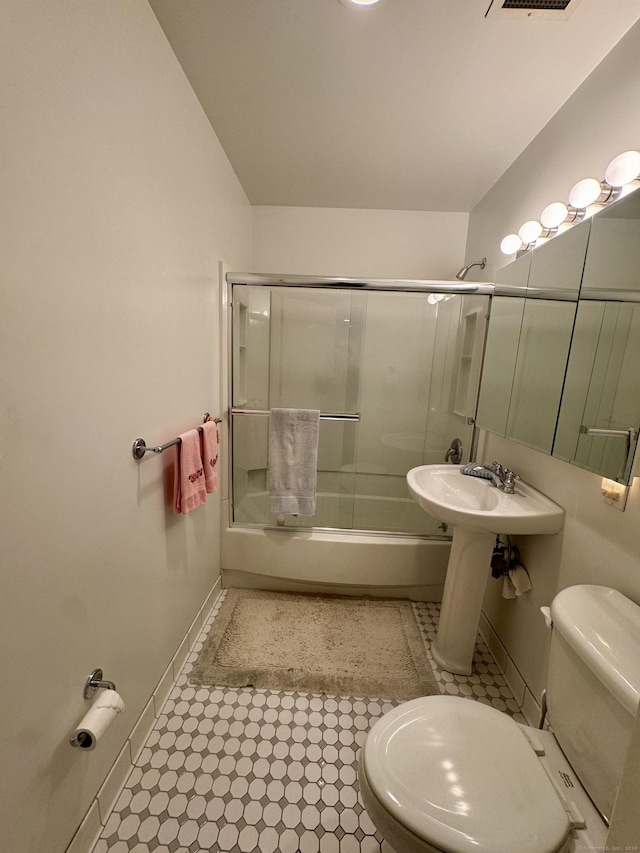 bathroom with shower / bath combination with glass door and toilet