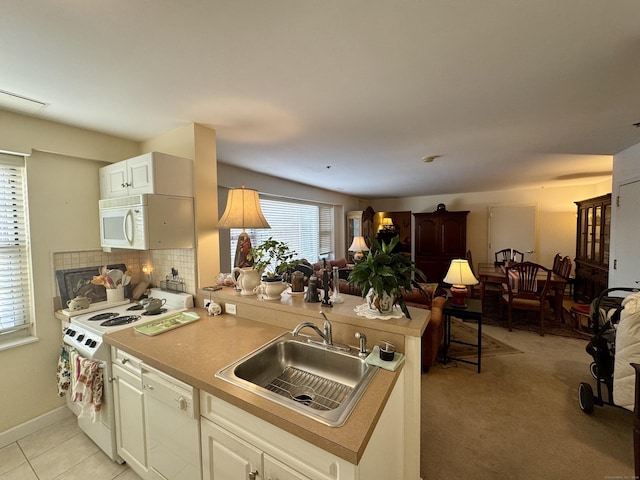 kitchen featuring sink, backsplash, kitchen peninsula, white appliances, and white cabinets