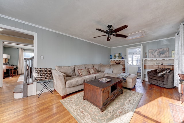 living room featuring ceiling fan, light hardwood / wood-style floors, ornamental molding, and a textured ceiling