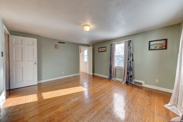 spare room with light wood-type flooring and a textured ceiling