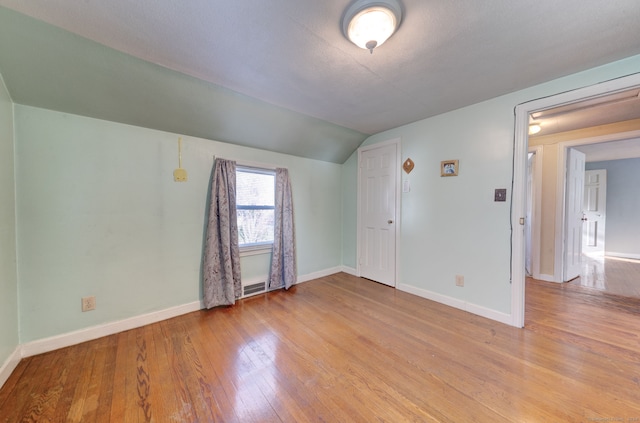 unfurnished room with light hardwood / wood-style flooring and lofted ceiling