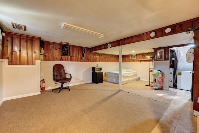 basement featuring wood walls, light carpet, and gas water heater