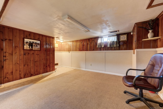 sitting room with carpet and wood walls