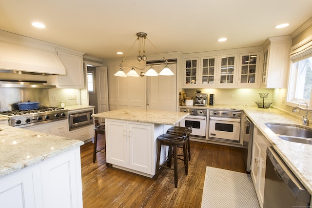 kitchen with a center island, white cabinets, decorative light fixtures, a breakfast bar area, and stainless steel appliances