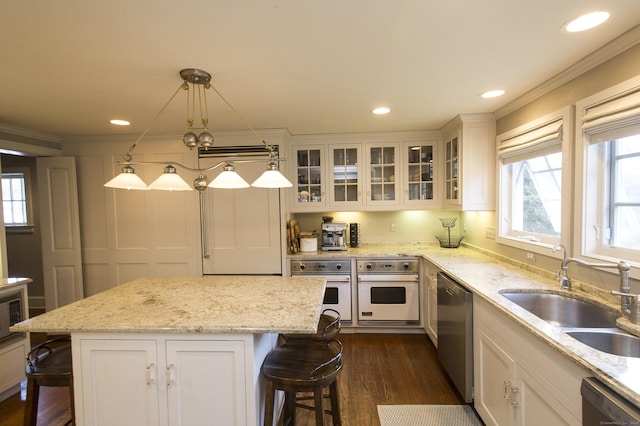 kitchen featuring a kitchen bar, white oven, sink, decorative light fixtures, and a kitchen island