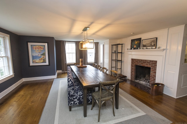 dining space featuring a fireplace, dark hardwood / wood-style floors, and an inviting chandelier