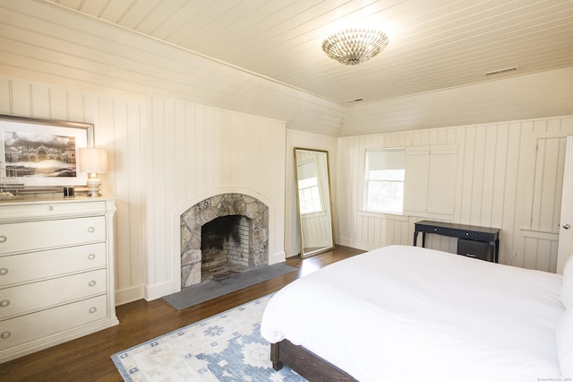 bedroom featuring lofted ceiling, dark wood-type flooring, and wooden walls