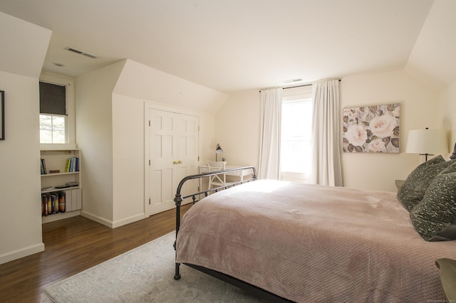 bedroom with a closet, vaulted ceiling, multiple windows, and dark wood-type flooring