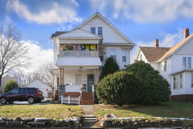 view of front facade with a porch, a balcony, and a front lawn