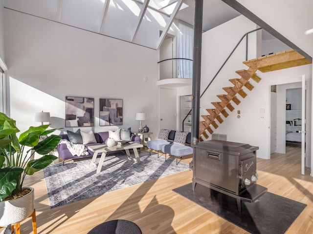 living room featuring wood-type flooring, a wood stove, and a high ceiling