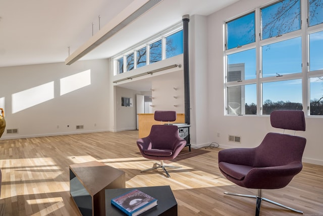 living room featuring a high ceiling, light wood-type flooring, and plenty of natural light