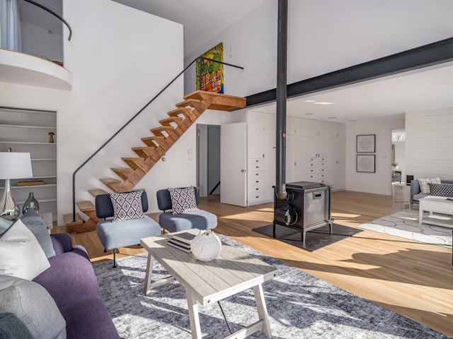 living room featuring a towering ceiling, light hardwood / wood-style floors, and a wood stove